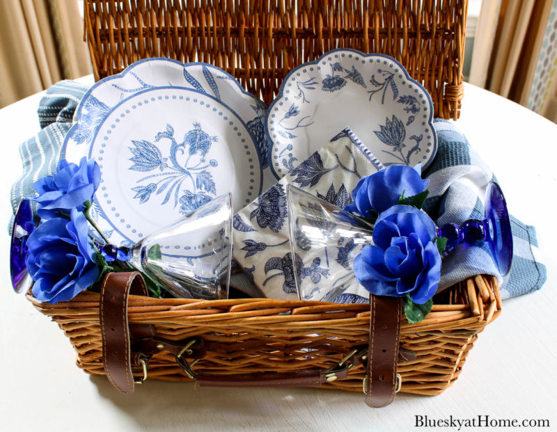 blue plates and napkins in wicker picnic basket