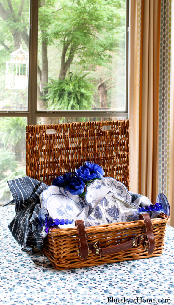 blue plates and napkins in wicker picnic basket