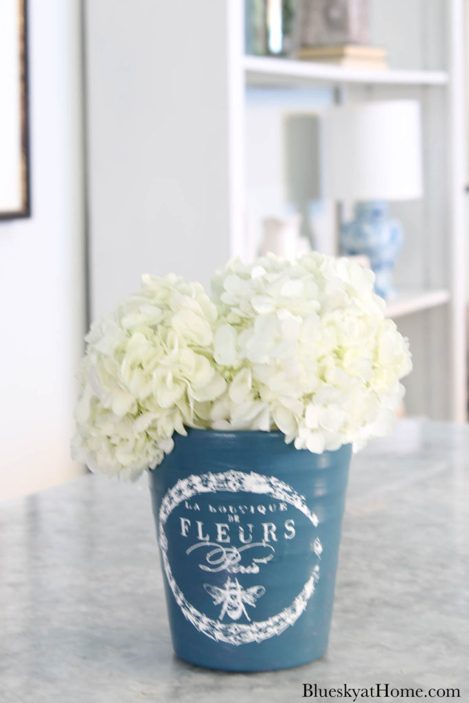 painted blue ceramic flower pot with white hydrangeas on counter