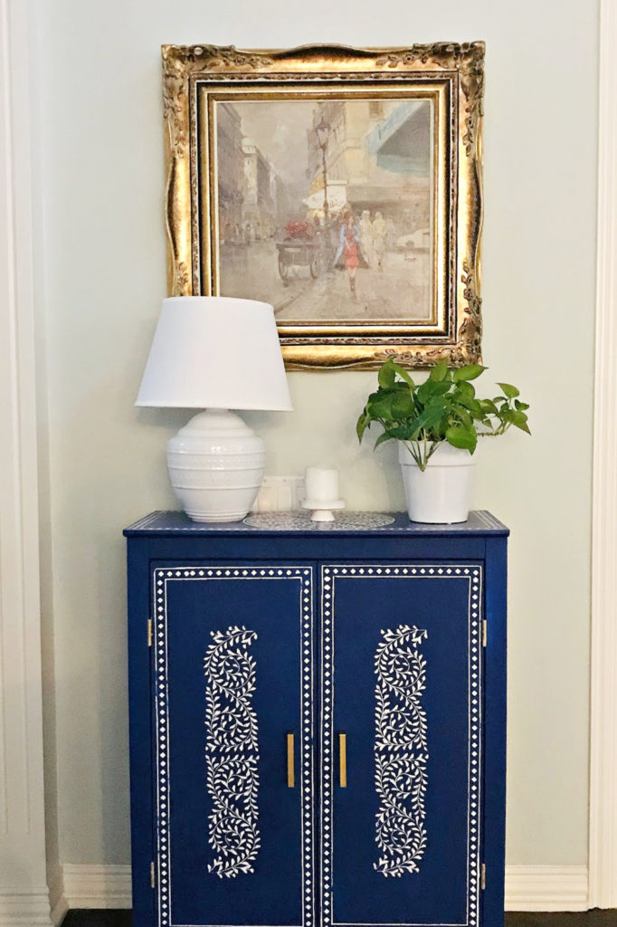 blue cabinet with white lamp and plant