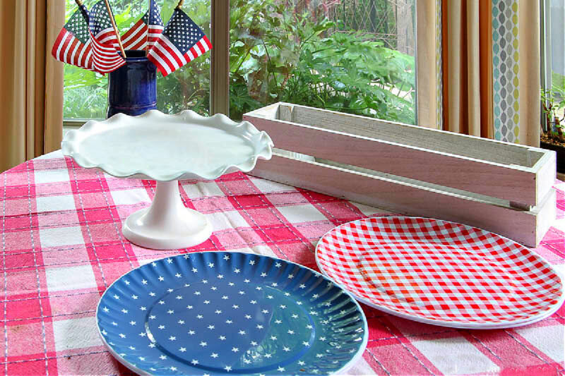 red, white, and blue plates, cake stand, white box, bue container with American flags