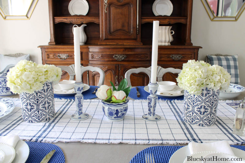 white hydrangeas in blue vase with candlesticks
