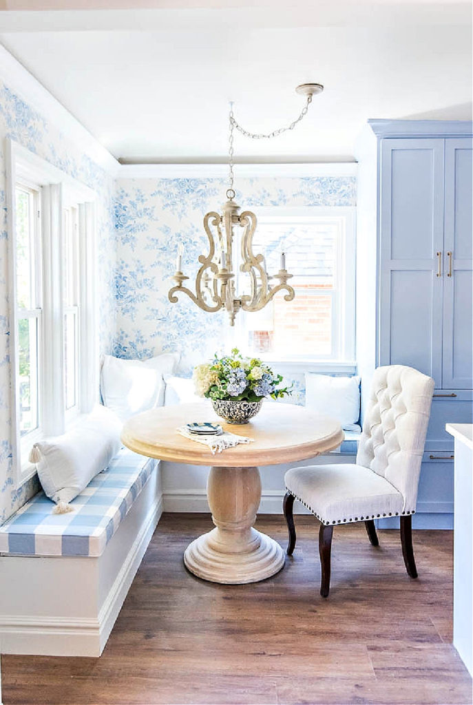 blue and white breakfast room with banquette and blue and white buffalo check cushion and blue floral wallpaper on one wall