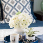 blue tray on bed with blue vase and diamond pattern on pillow
