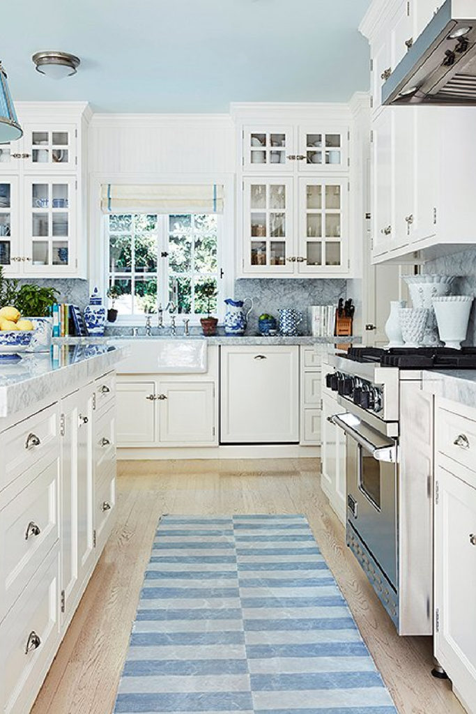 blue and white kitchen with blue backsplash and blue rug and accessories