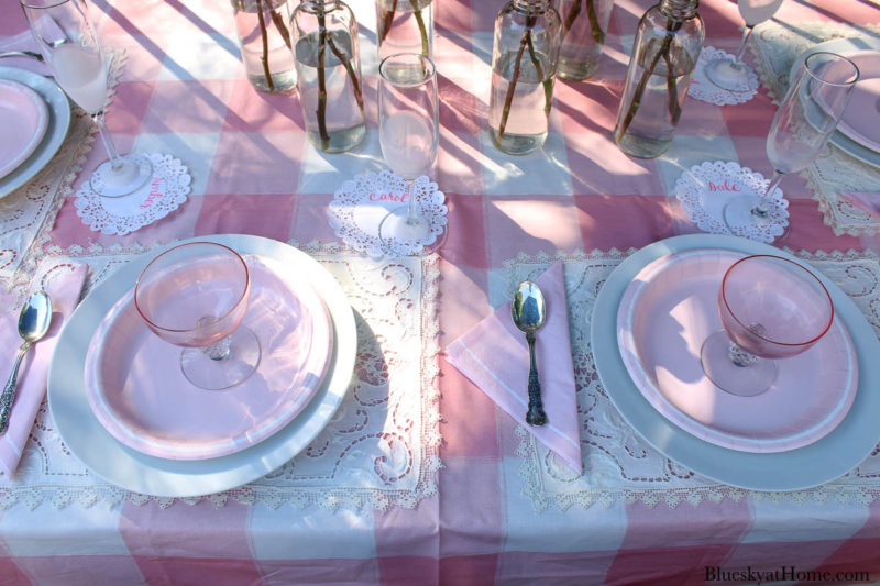 pink roses in bottles on pink table setting