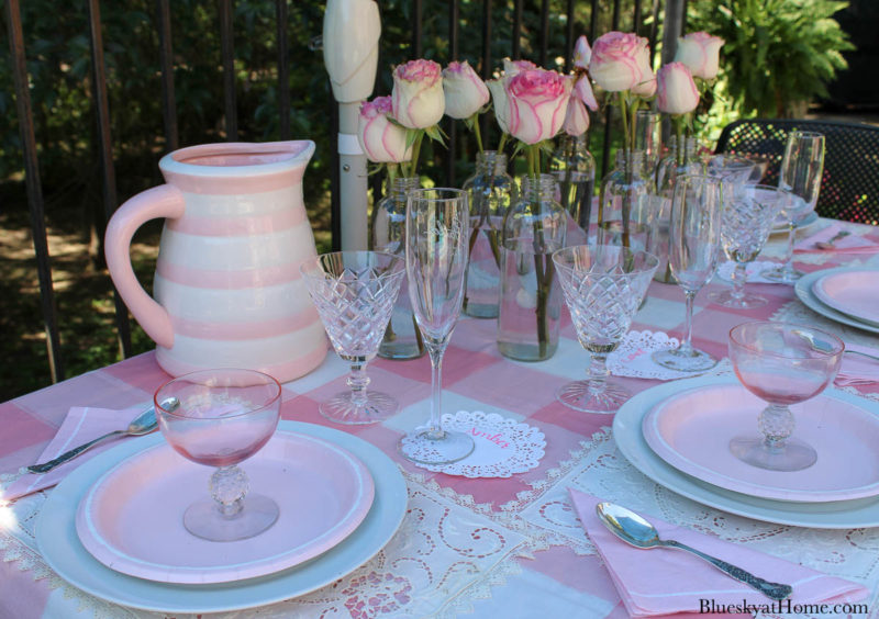 pink roses in bottles on pink table setting