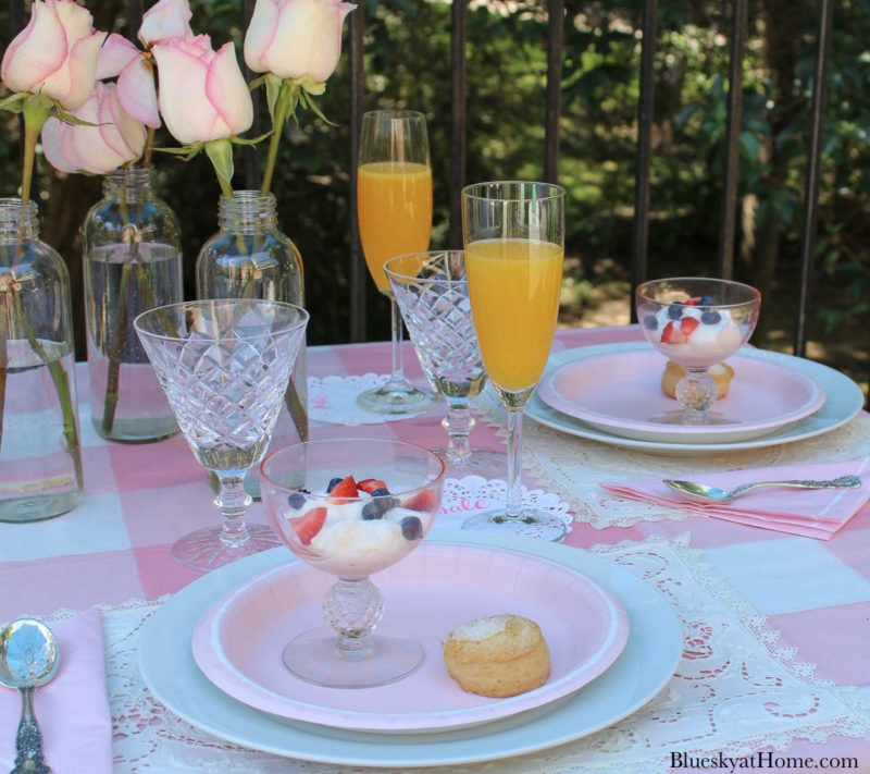 pink table with bowl with yogurt and strawberries and blueberries