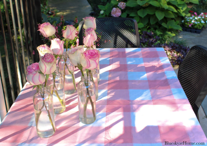 pink and white table cloth with pink roses in bottles