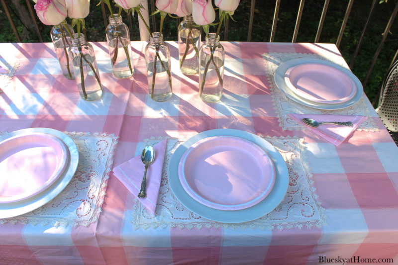 pink roses in bottles on pink table setting