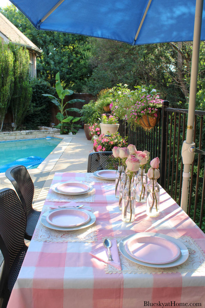 pink check tablecloth with pink roses in glass bottles and pink plates