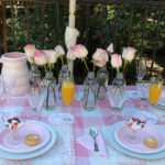 pink roses in bottles on pink table setting