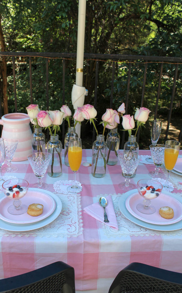 pink roses in bottles on pink table setting