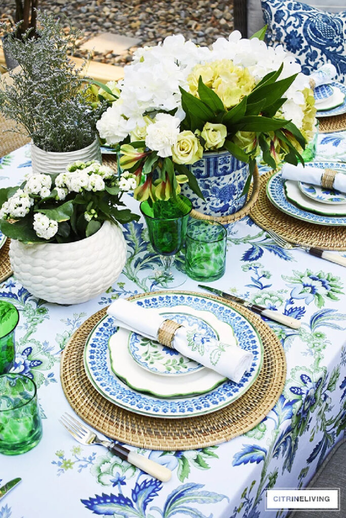  blue and green floral tablecloth with blue plates and planter on the table