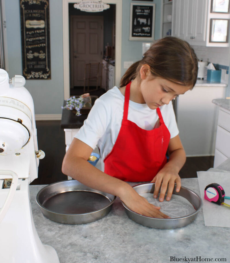 girl greasing cake pans