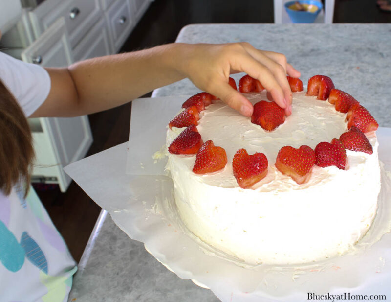 heart~shaped strawberries on white vanilla cake
