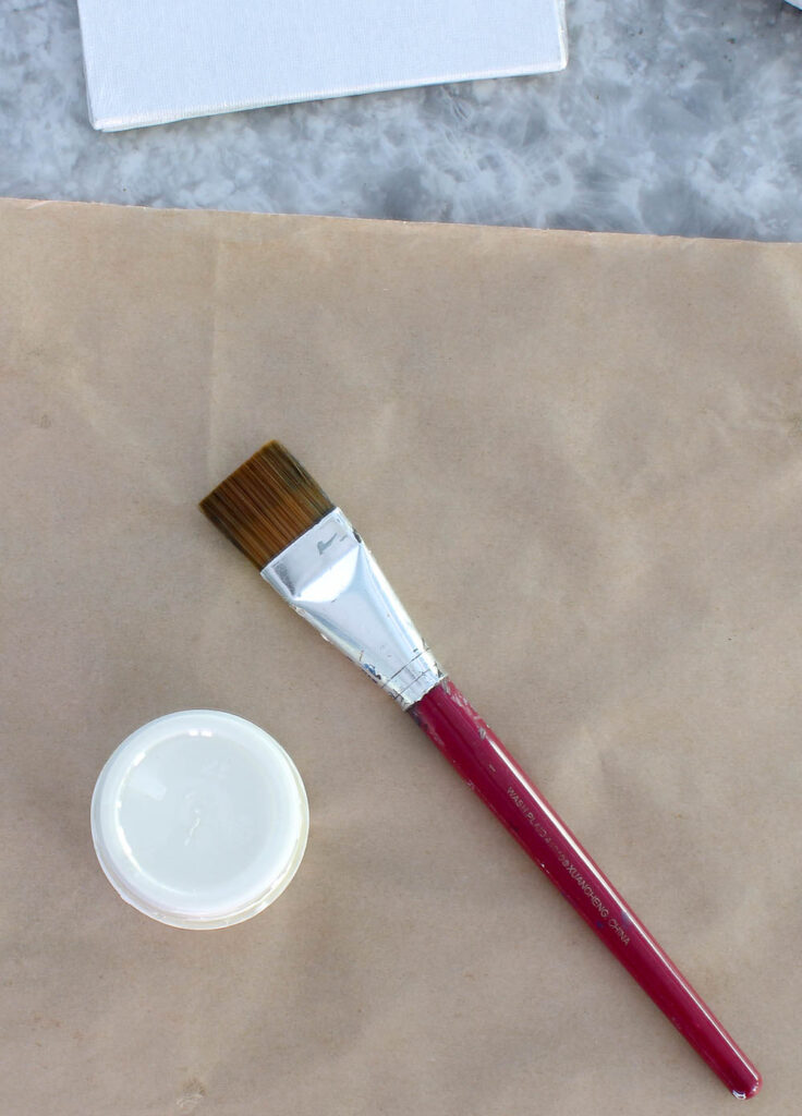 cream colored paint in jar and paint brush