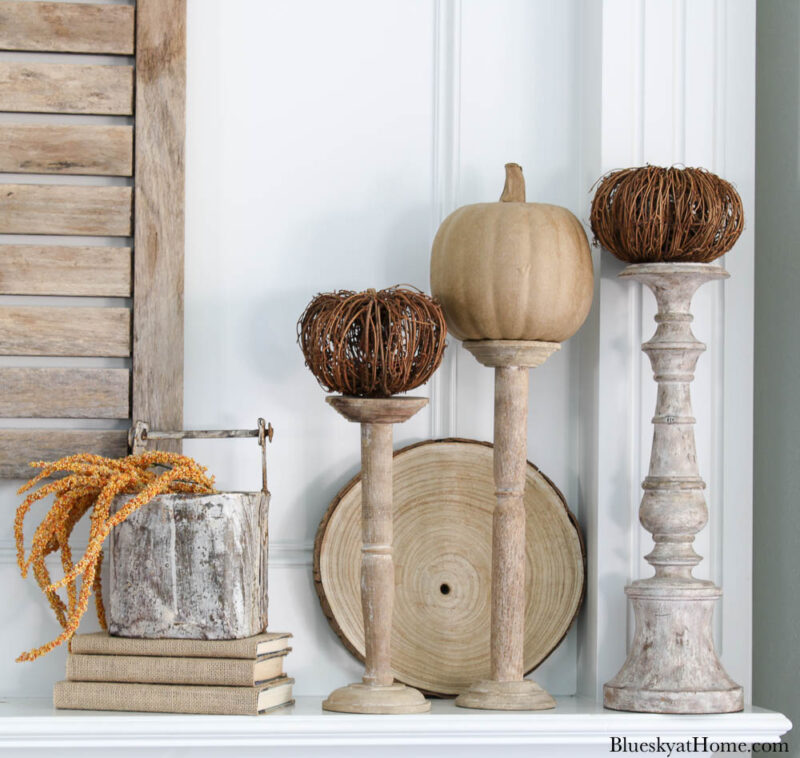 netural pumpkins on candlesticks on fall mantel