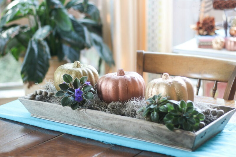 wooden tray filled with spanish moss and painted pumpkins
