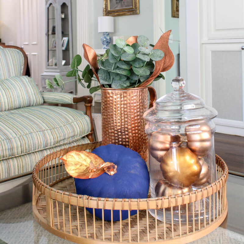 blue pumpkin and copper pitcher on woven tray