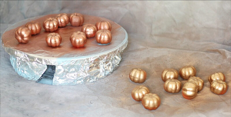 spray painting small pumpkins in metallic colors