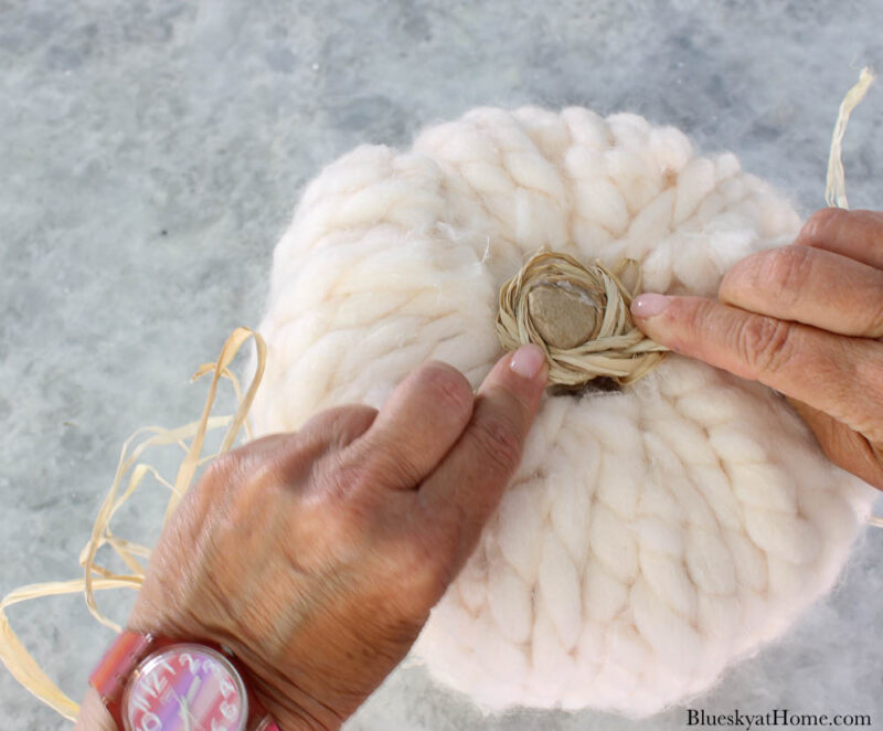 tying raffia to pumpkin with yarn