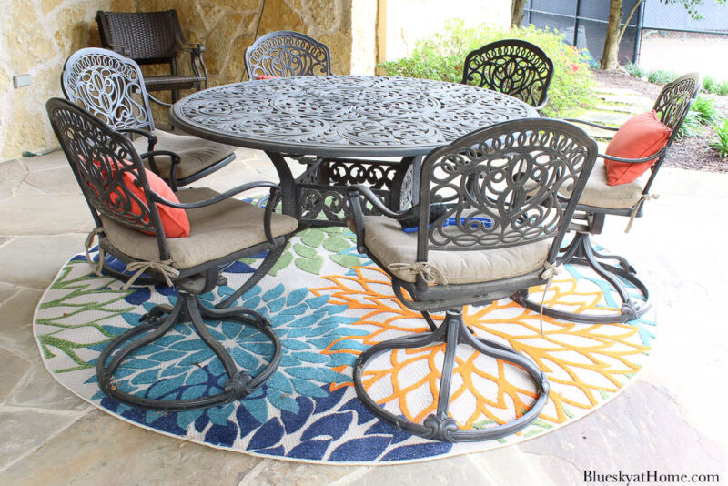 wrought iron round dining table on rug and stone patio