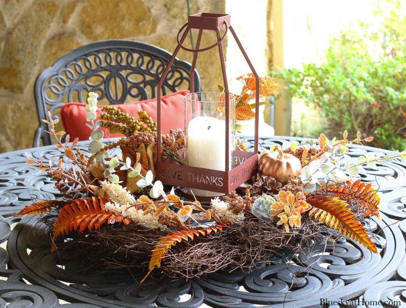 round grapevine wreath with leaves on table with lantern and candle