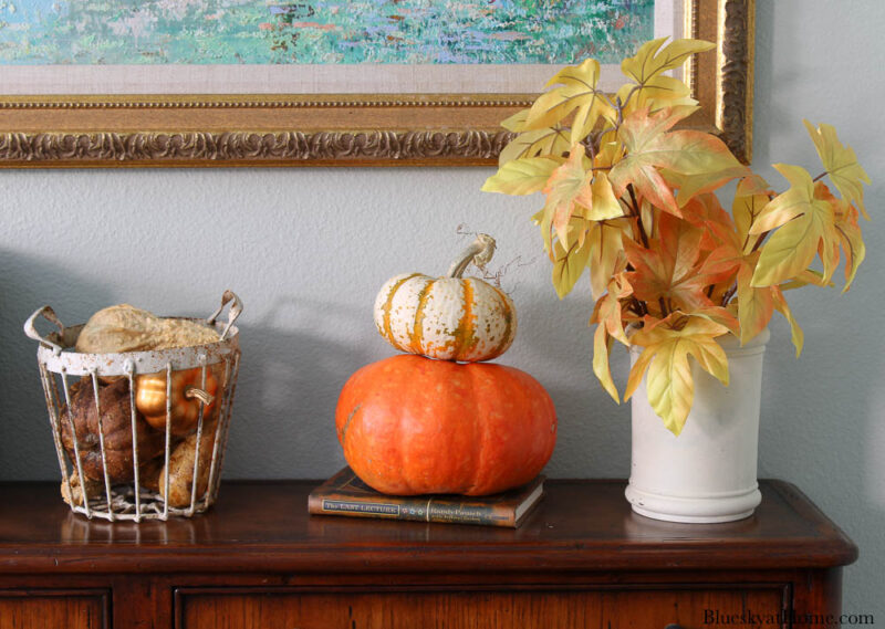 fall foliage in white vase with orange pumpkins