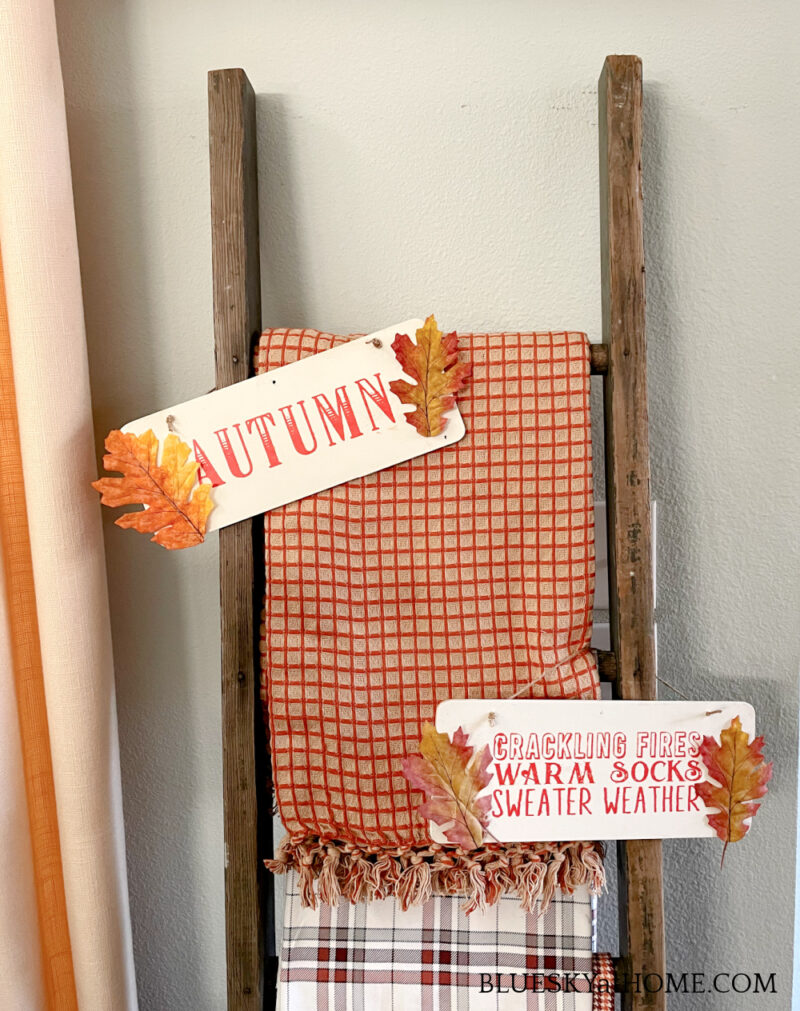 fall colored throws on vintage ladder and wood signs