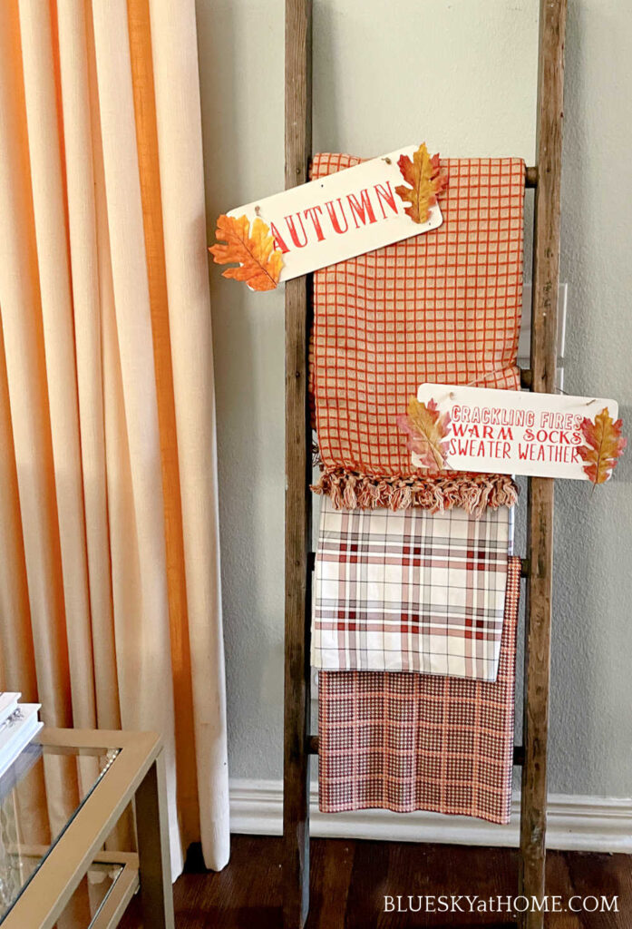 fall colored throws on vintage ladder and wood signs