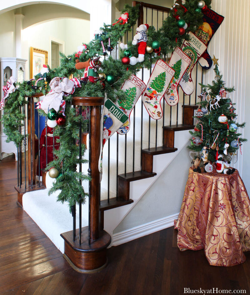 banister with garland and stocks and small Christmas tree