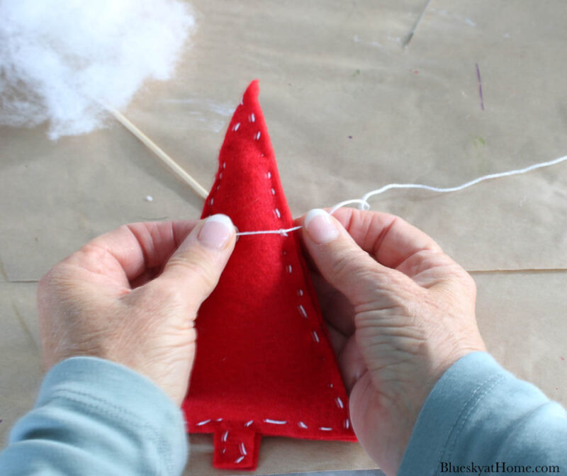 tieing thread on back of red felt Christmas trees