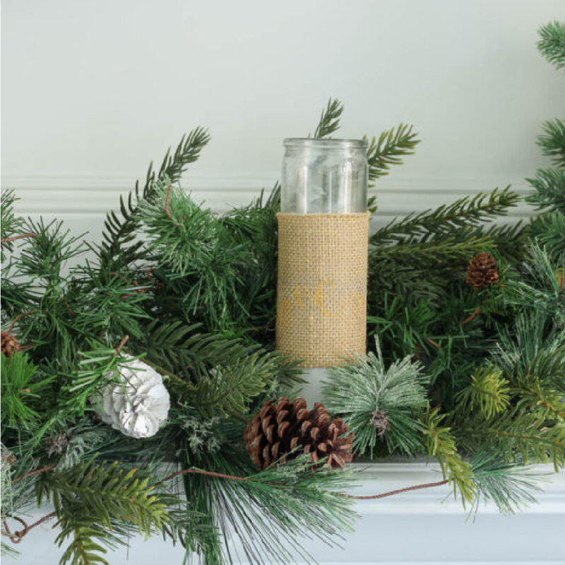 burlap wrapped candle with winter greenery on white mantel
