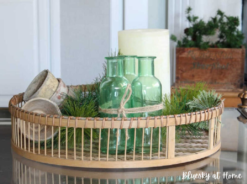 green and white winter decor with green bottles on woven tray