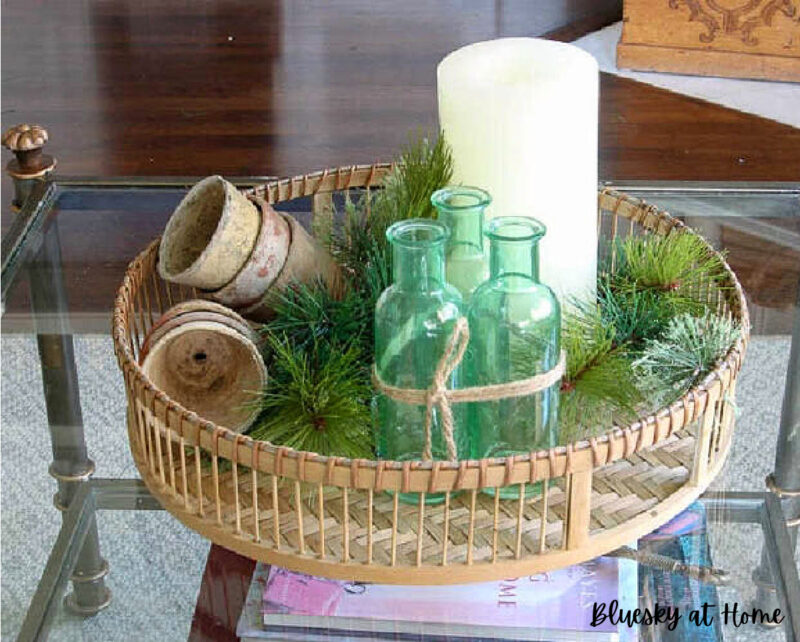 green bottles and candle on woven tray