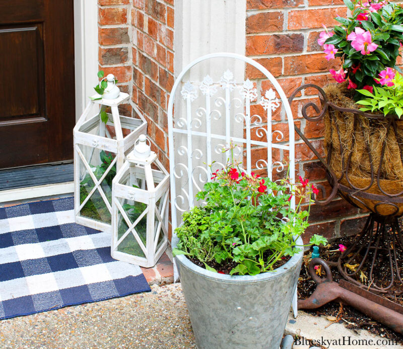 flowers in galvanized planter with white lanterns by front door