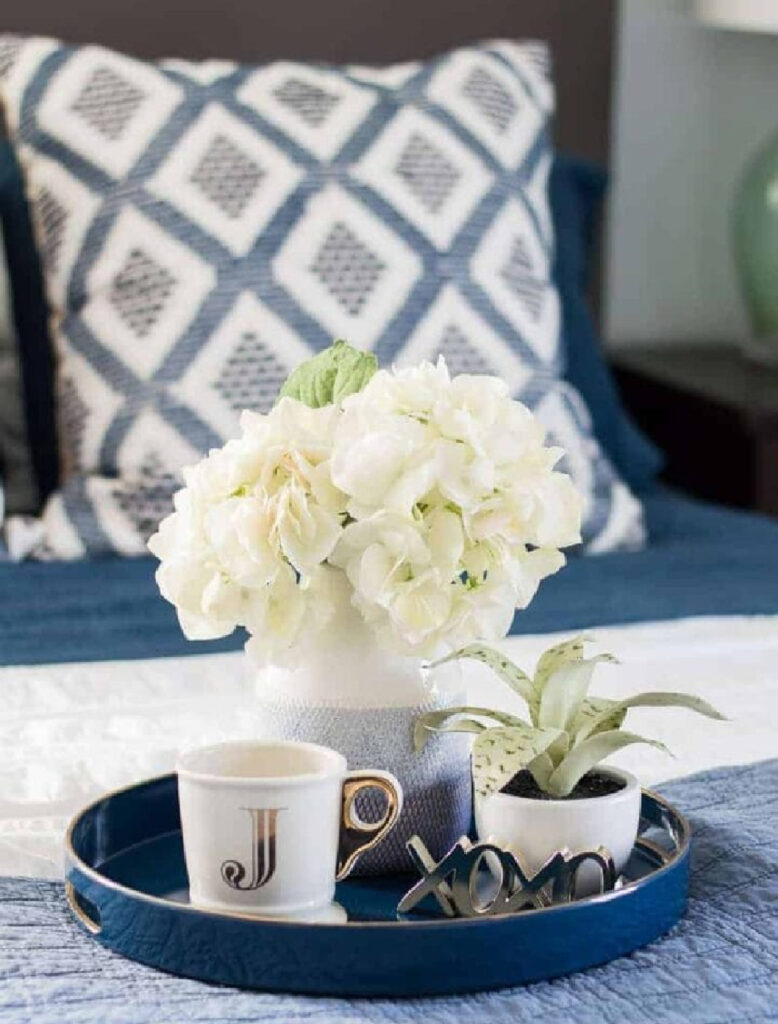 white hydrangeas on a blue tray on a bed