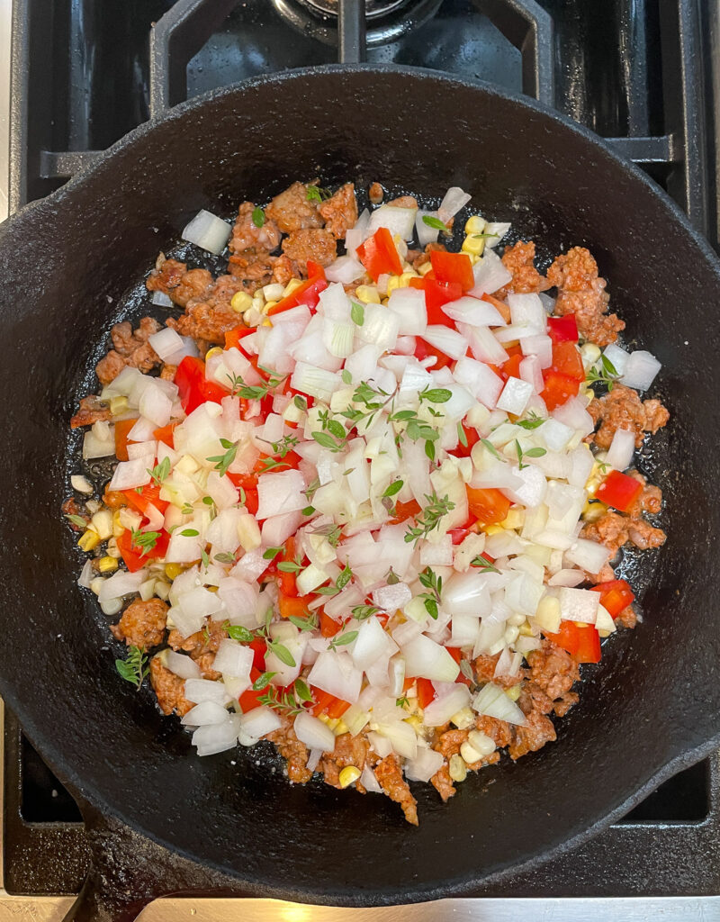 making maque choux with andouille sausage and okra and onion in cast iron skillet