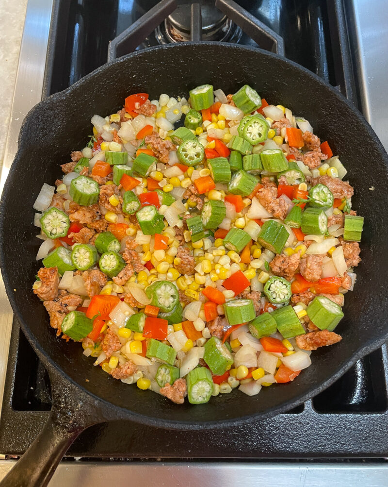 making maque choux with andouille sausage and okra in cast iron skillet