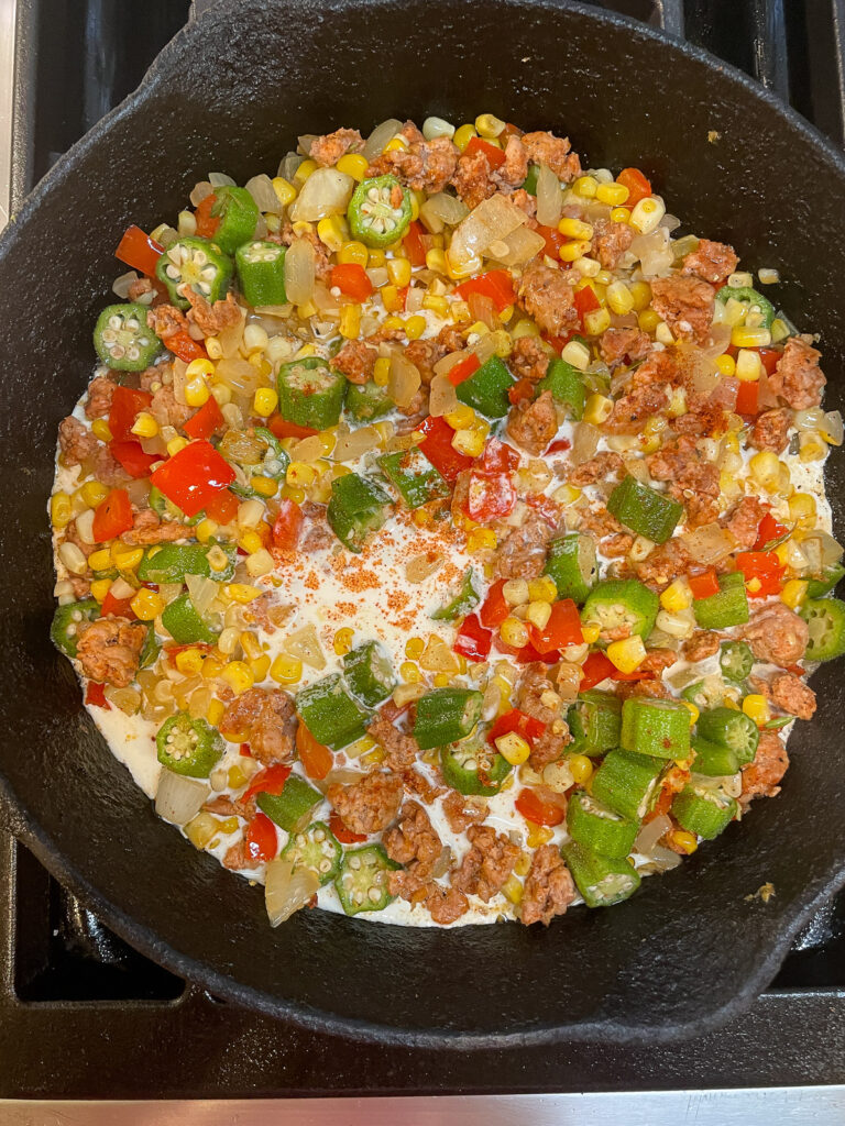 making maque choux with andouille sausage and okra in cast iron skillet