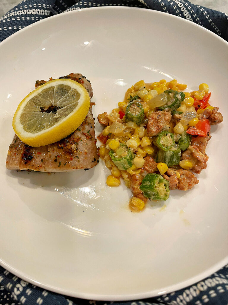 maque choux with andouille and okra on white plate