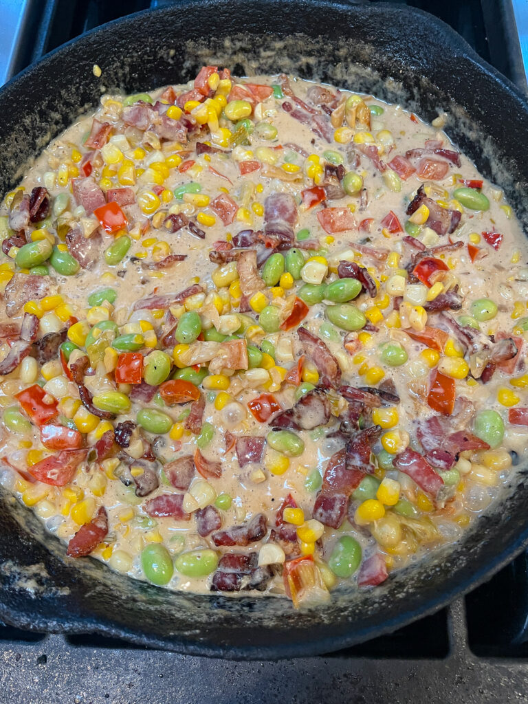 making maque choux with cream, edamame and bacon in skillet