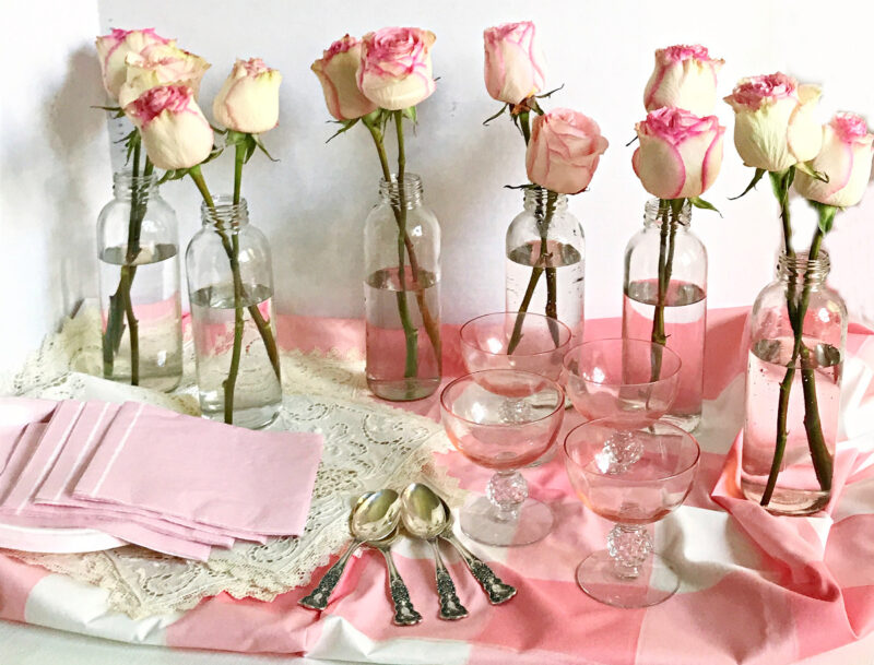 glass bottles and pale pink flowers with silverware