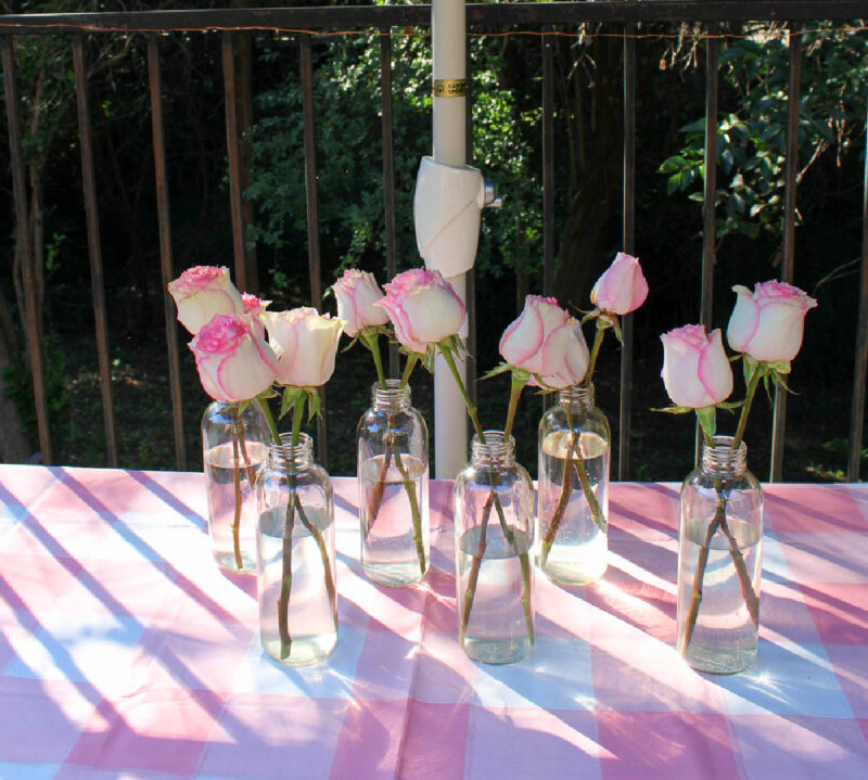 pink check tablecloth with pink roses in glass bottles