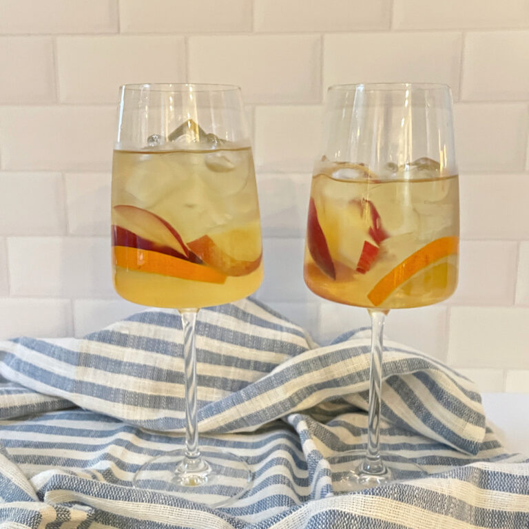 white wine sangria in two wine glasses with fruit garnish
