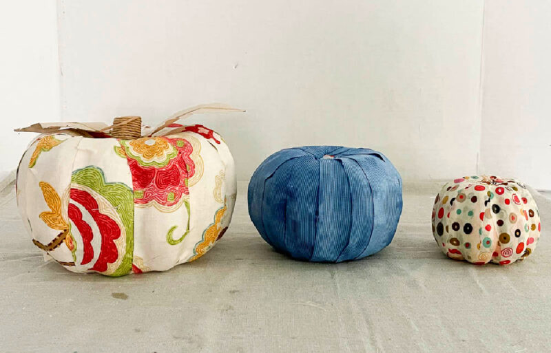 three fabric-covered pumpkins in a floral, demin, and dot pattern