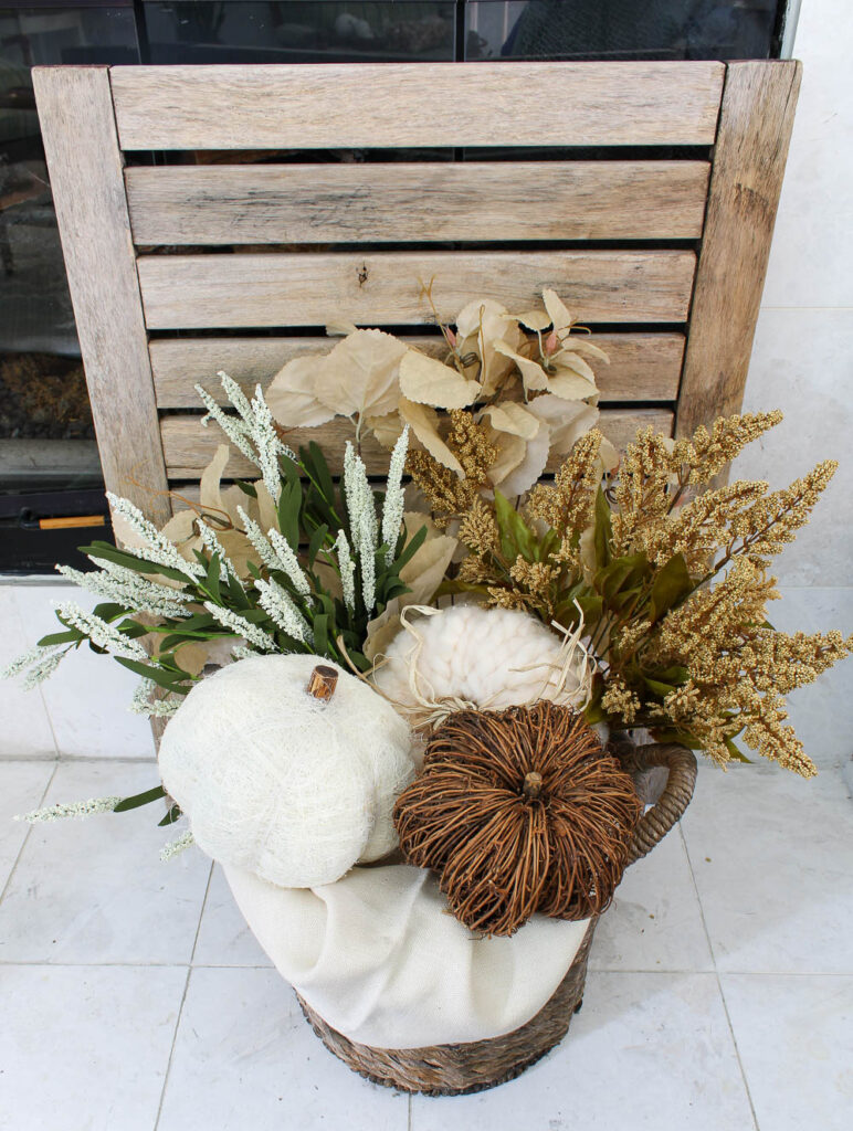 basket of fall foliage in front of wood slats