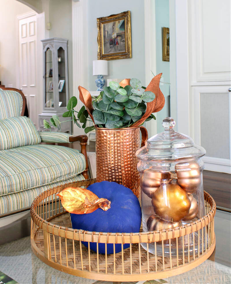 fall vignette with warm metallics of gold leaves and pumpkins and copper pitcher