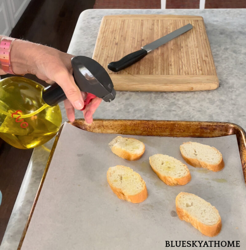 spraying olive oil for cranberry and ricotta crostini